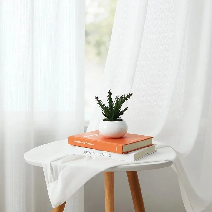 white sheer curtain draped beside a table