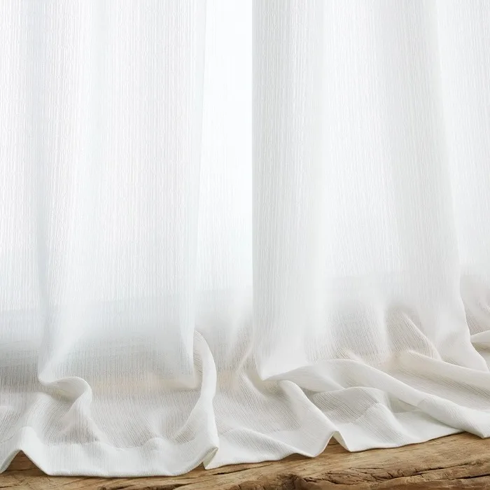 white sheer curtain hem pooling on a wood floor