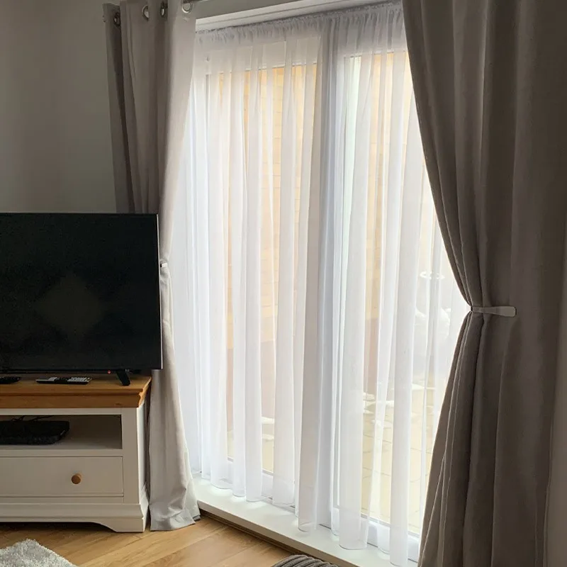 Sheer curtain layered over blackout drape in a modern bedroom