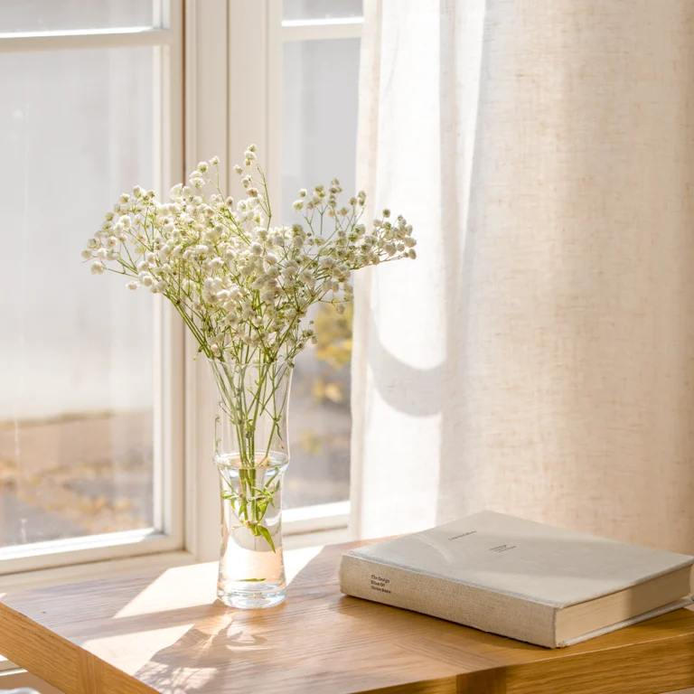 linen-look sheer curtain beside flowers and books