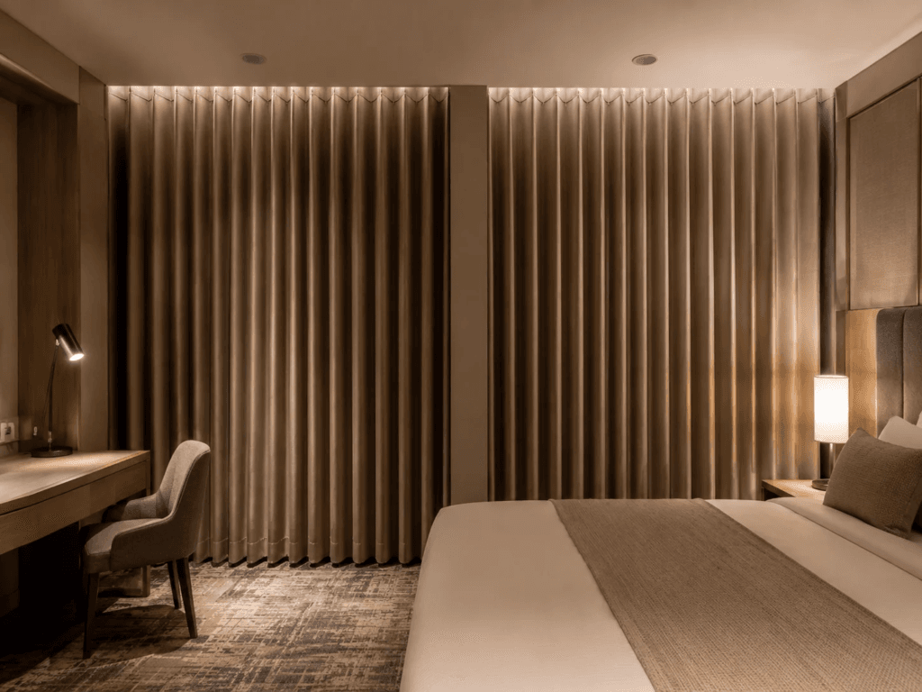 Hotel guest room blackout curtains in beige with consistent Ripplefold heading folds