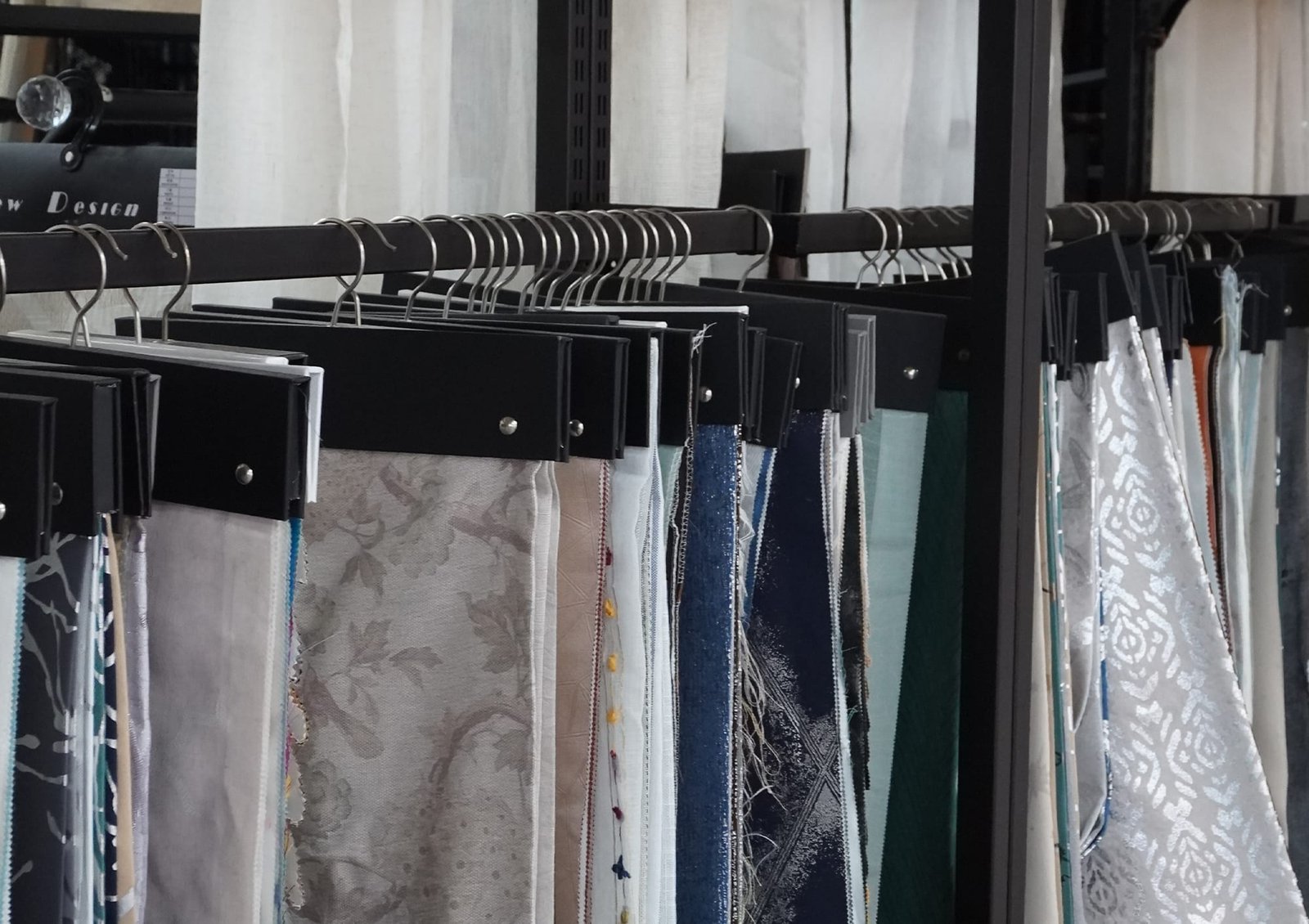 Curtain fabric swatch cards and sample hangers on a showroom display rail