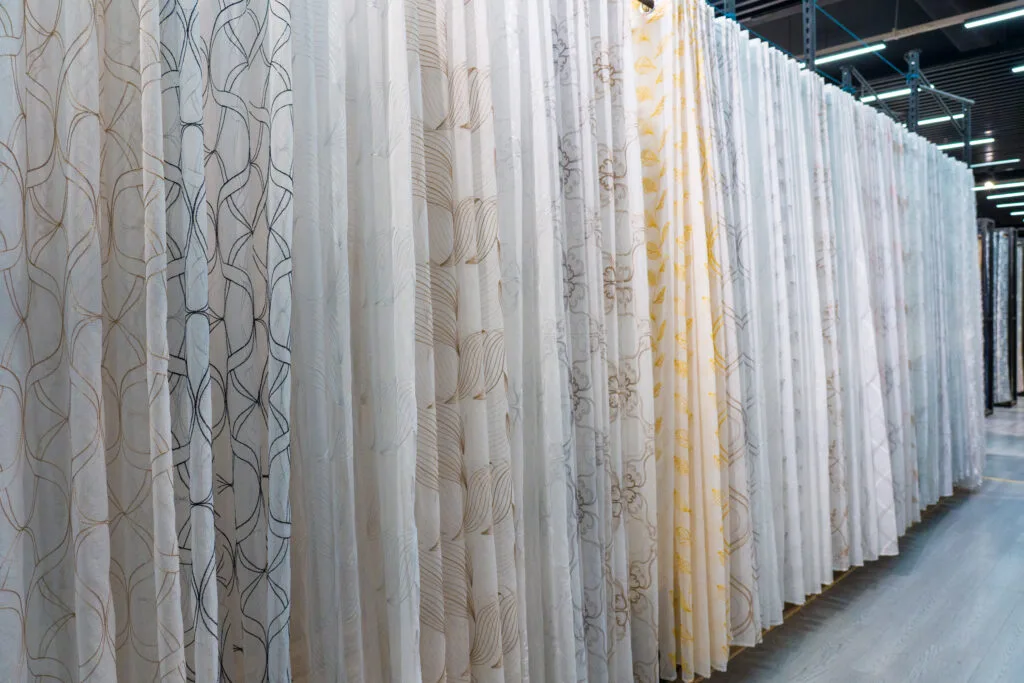 Rows of sheer embroidered curtain fabrics hanging in the Dairui showroom