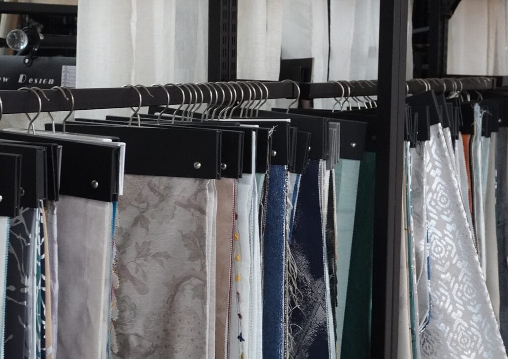 Curtain fabric swatch cards and sample hangers on a showroom display rail
