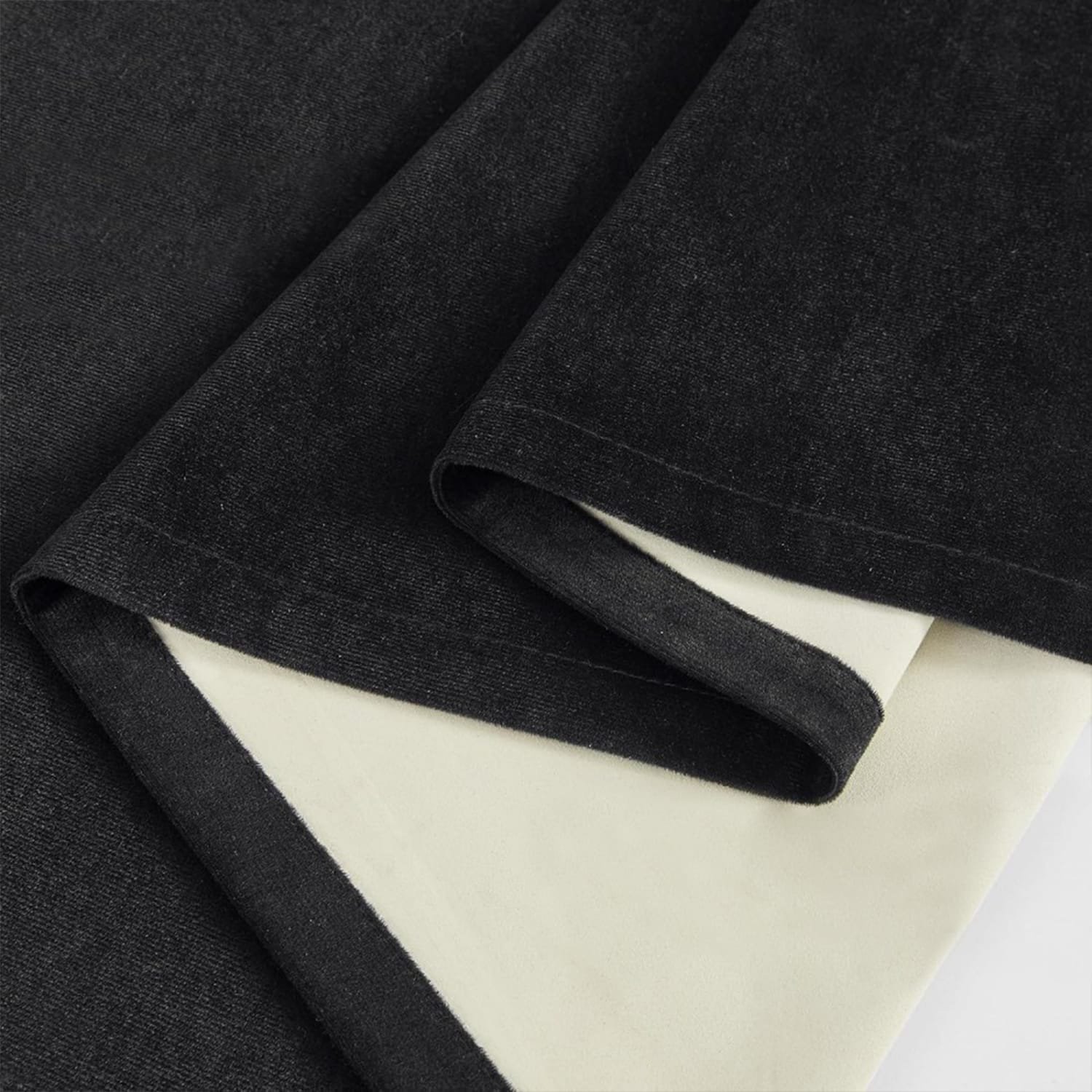 Black blackout fabric showing face and light-colored coated backing
