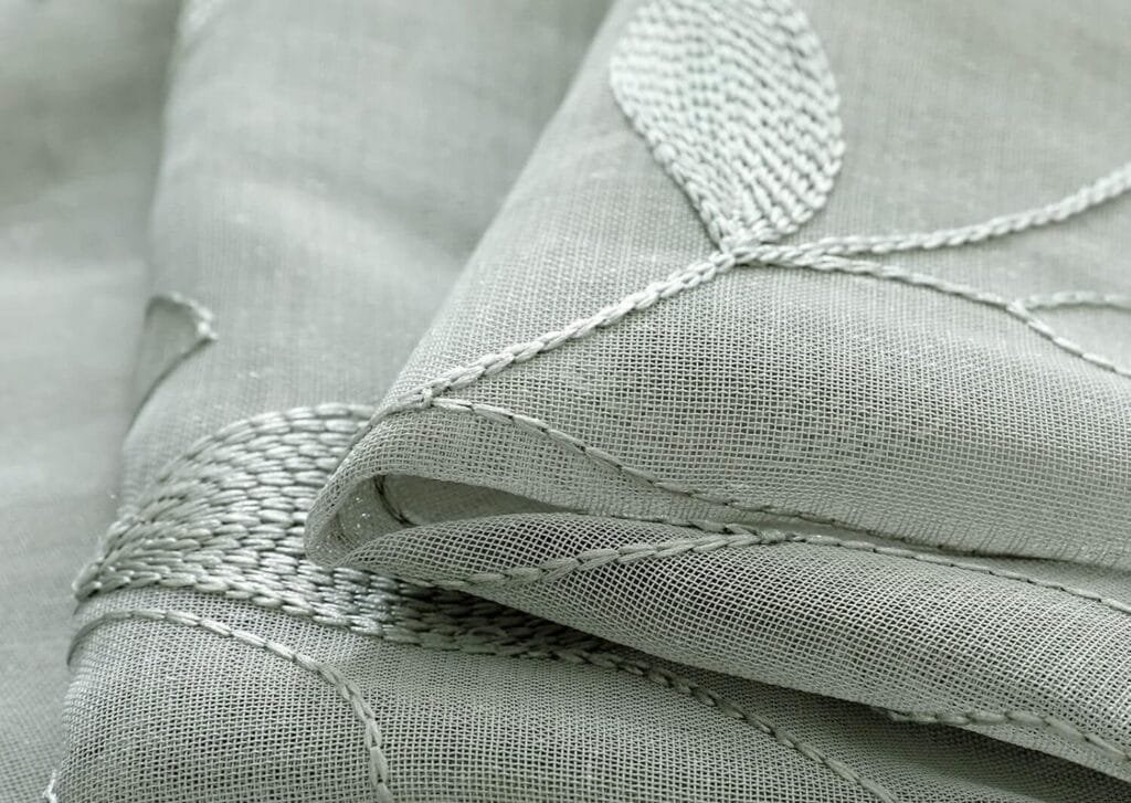 Close-up of embroidered sheer fabric stitches and base cloth